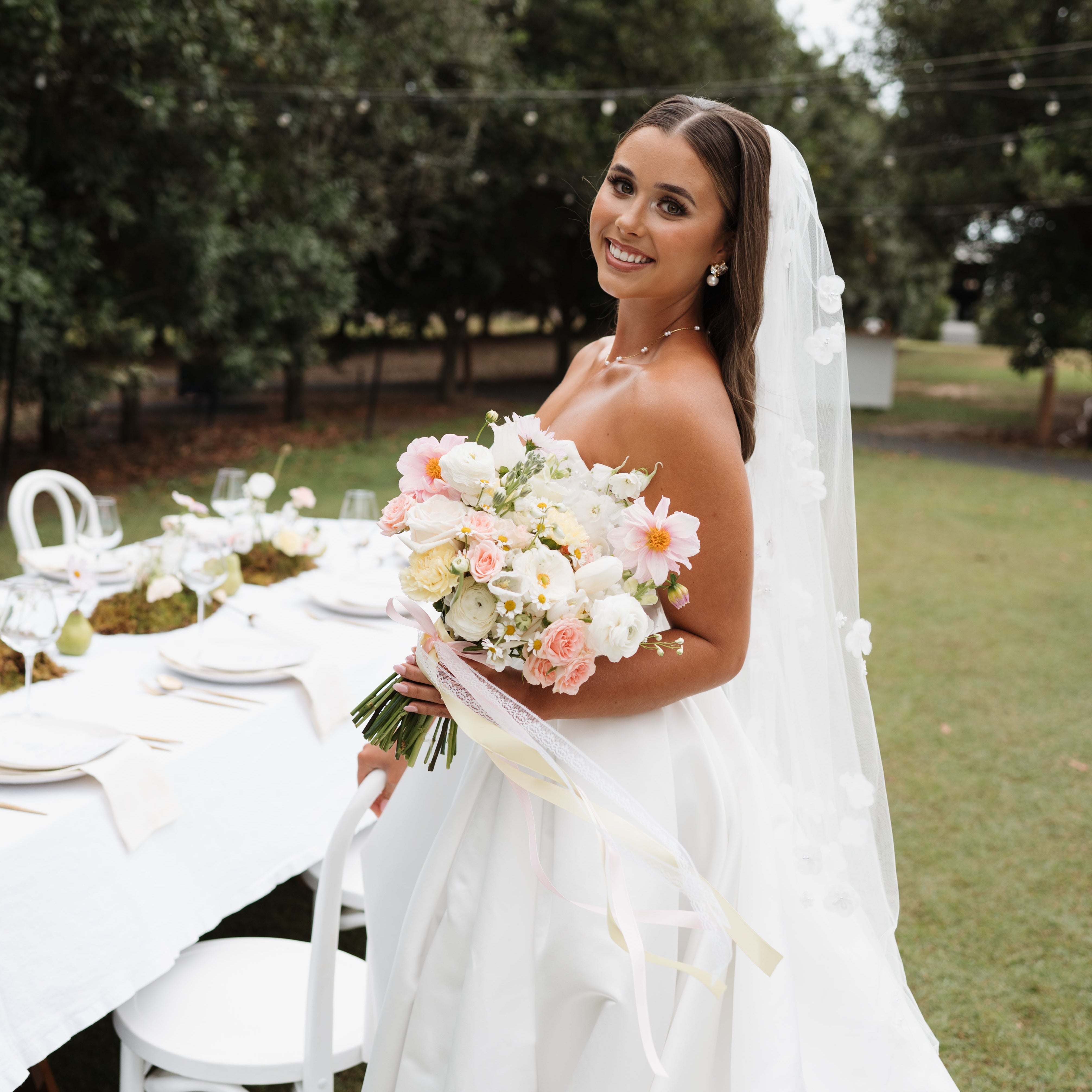 Bride holding a romantic bridal bouquet at an outdoor wedding reception, by Posy Mae Floral Studio Bundaberg Queensland wedding florist.